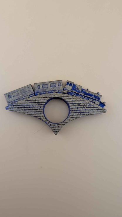 Full profile view of the blue and gold textured train and brick bridge page holder against a white background.