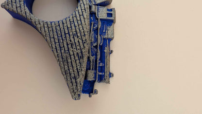 Extreme close up showing the textured bridge and the detailed mechanical structure of the blue train engine from the side.
