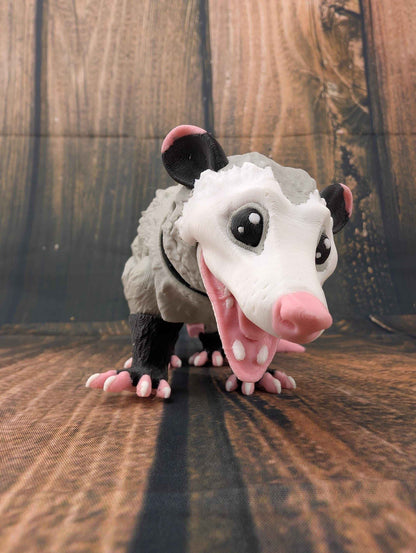Articulated grey and white opossum figurine snarling with its mouth wide open, viewed from the front.