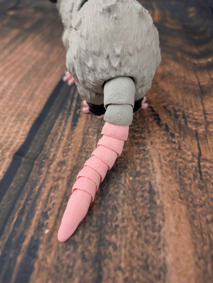 Extreme close-up showing the segmented pink tail connection point against the grey textured body fur.