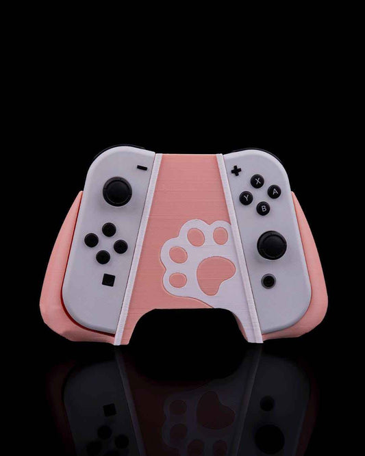 Front view of a two-tone pale pink and white controller grip featuring a paw print cutout, holding two gray Joy-Cons.