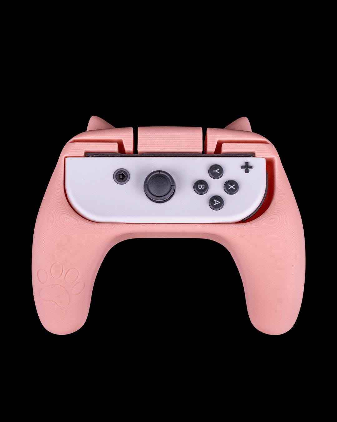 Straight-on view of the pink controller grip featuring white cat ears and a large white paw print decal.
