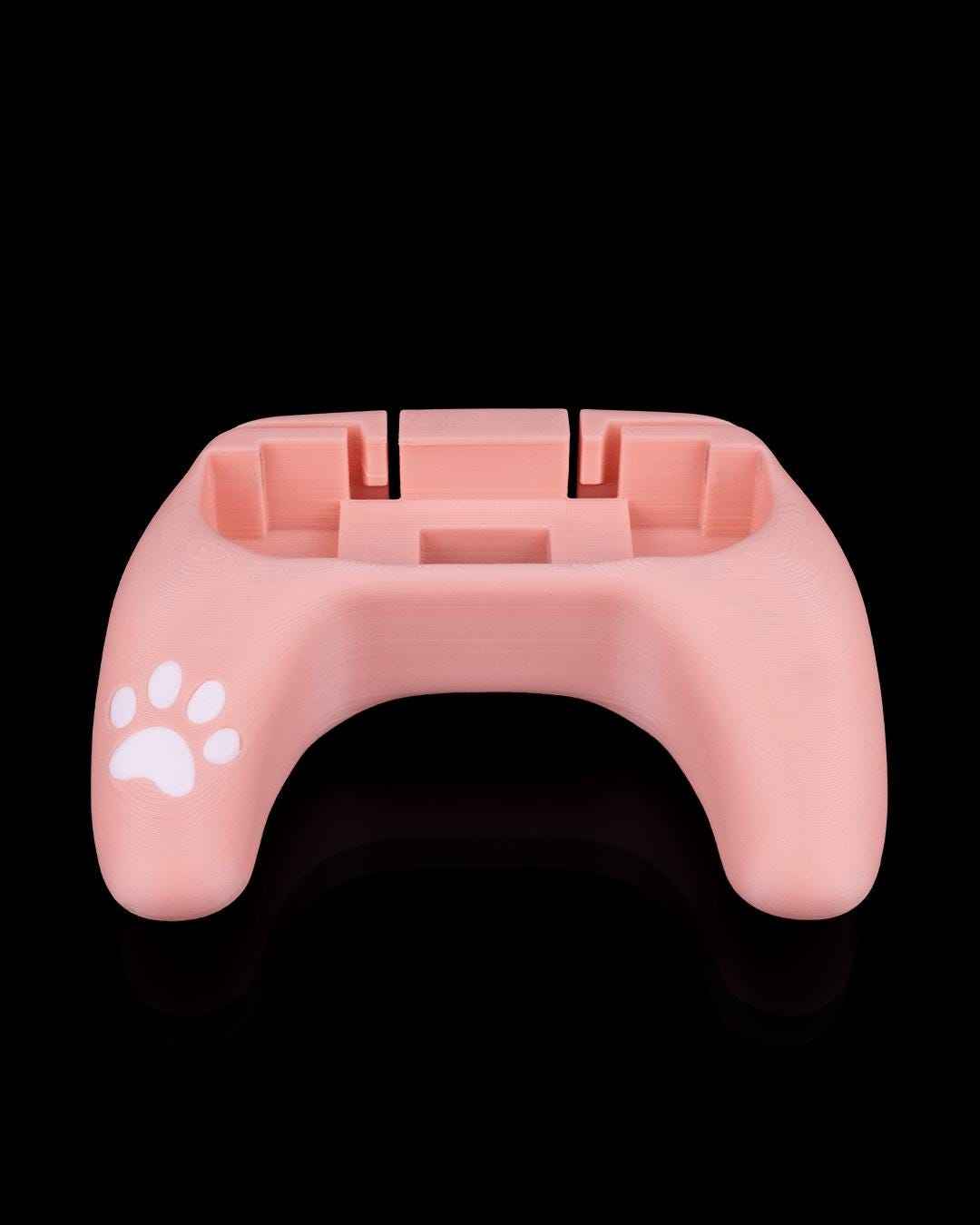 Rear view of the empty, U-shaped soft pink controller grip shell. White paw print visible on the left side.