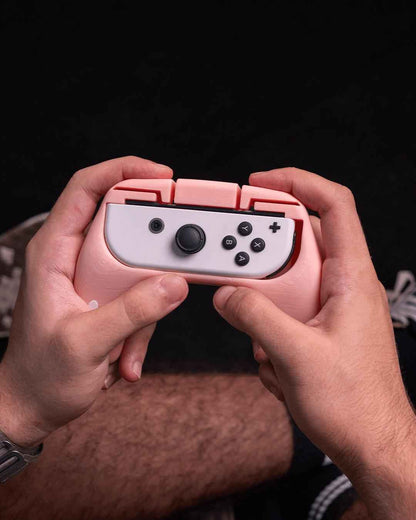 Close-up of two hands gripping the matte pink, cat-eared controller accessory while playing.