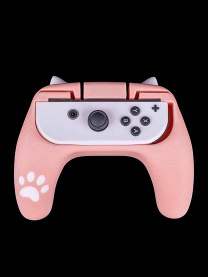 Front view of a soft pink controller grip with white cat ears and a paw print decal, holding a white joycon.
