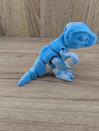 Close up side profile of the crouching two-tone blue articulated dinosaur toy on wood.