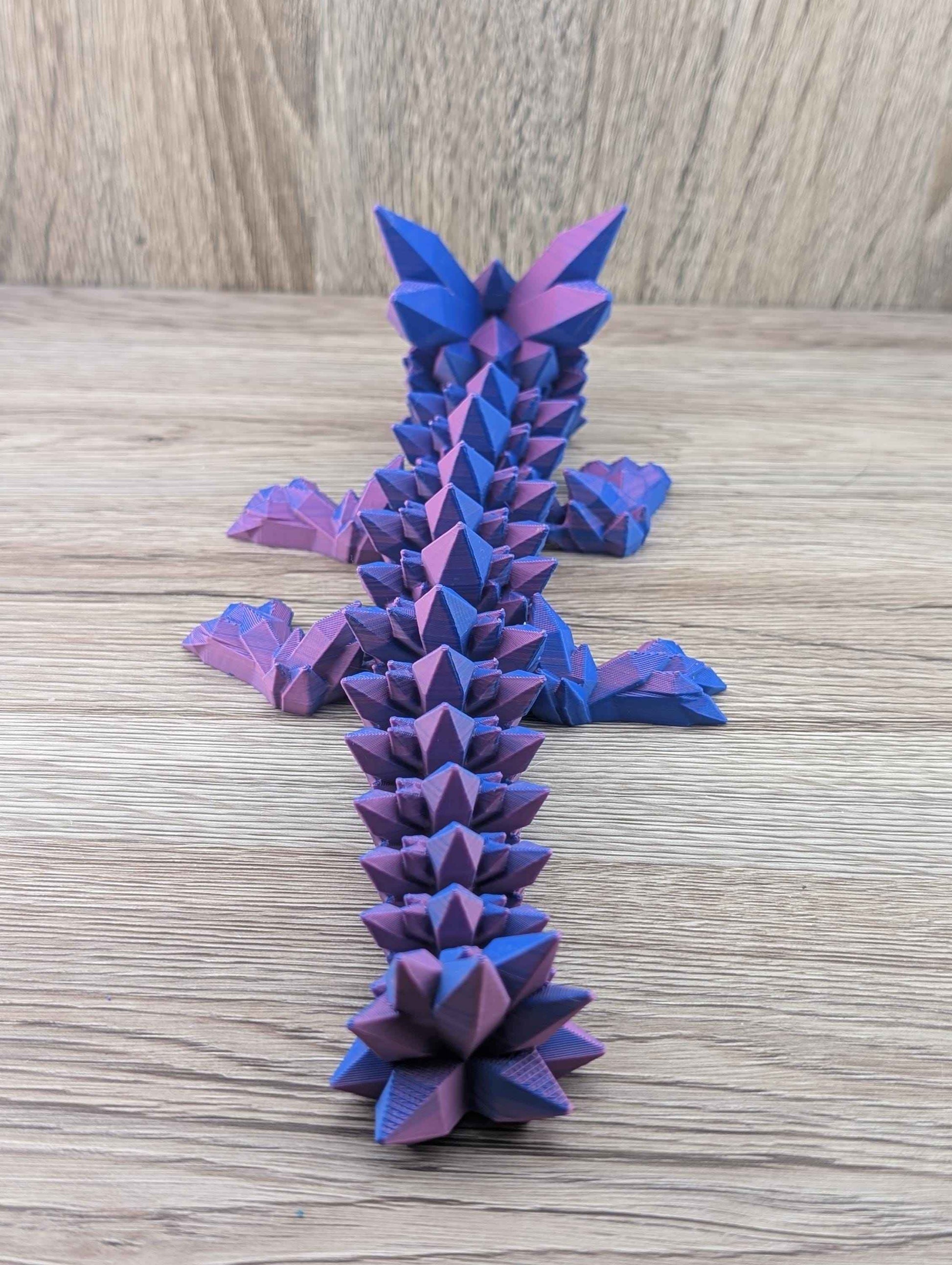 Rear perspective looking straight down the segmented spine of the blue and purple crystal dragon fidget toy.