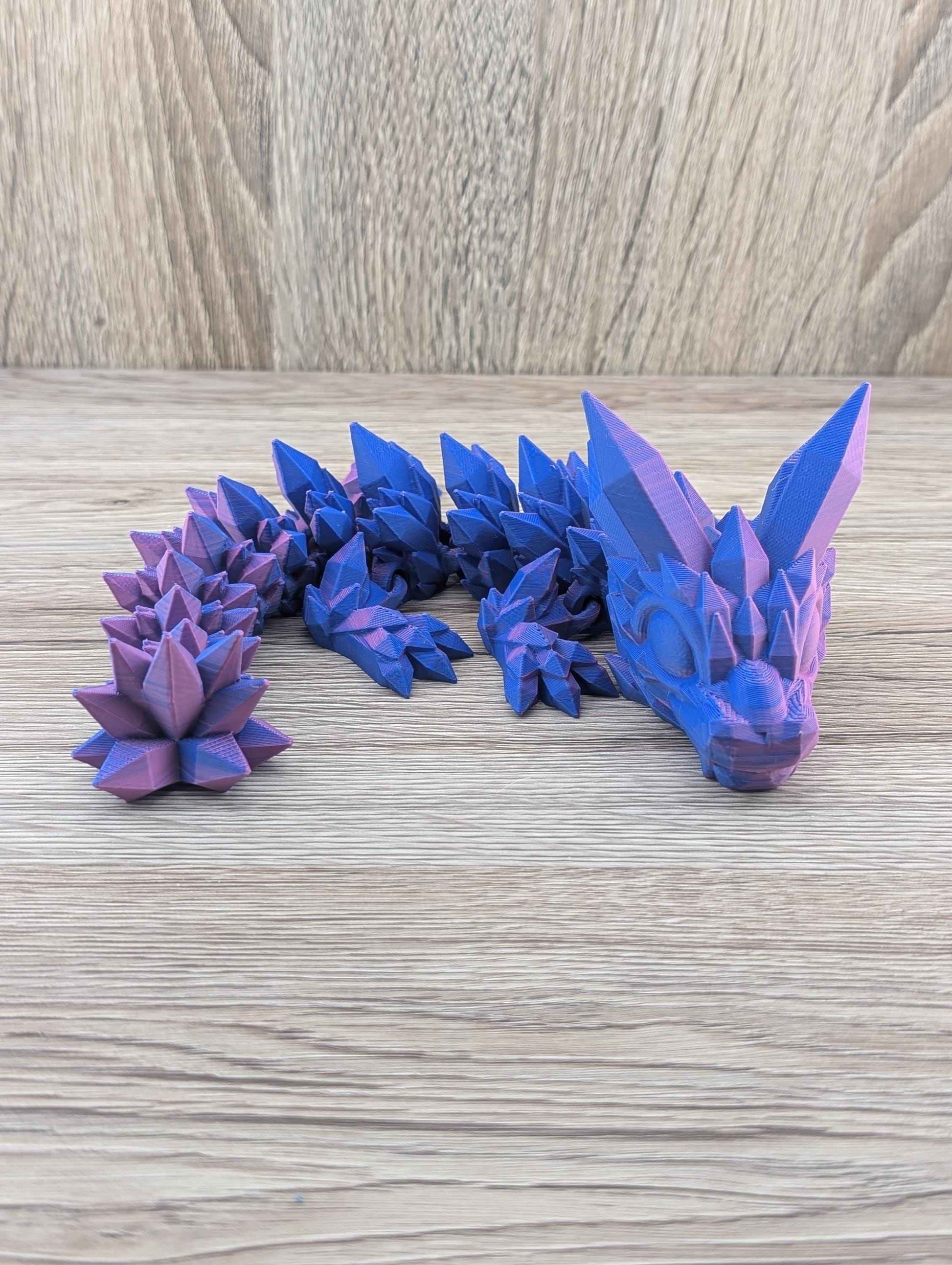 Full side profile of the articulated crystal dragon figure, showing its segmented body and vivid purple and blue color shift.
