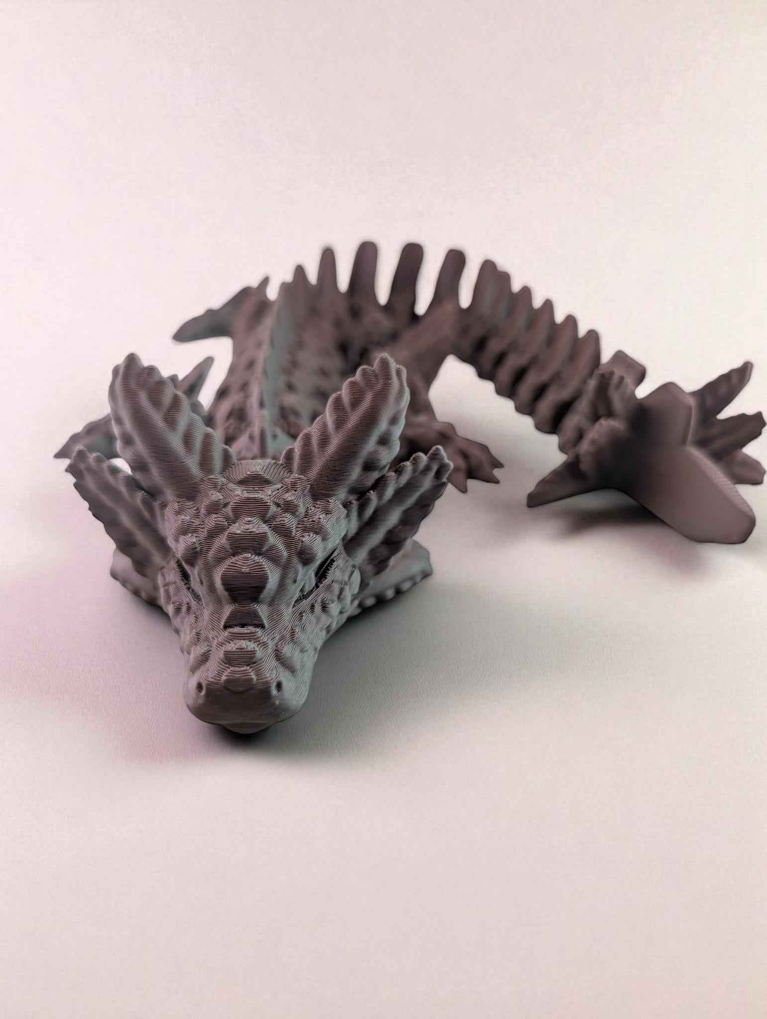 Matte articulated dragon figure, front-facing view, showing spiny crest and segmented tail.