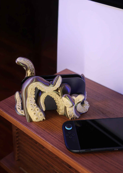 Olive and brown kraken console stand detailed with prominent suction cups, next to a black gaming device.